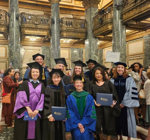 graduates and faculty posing in their robes in the Carnegie Music Hall