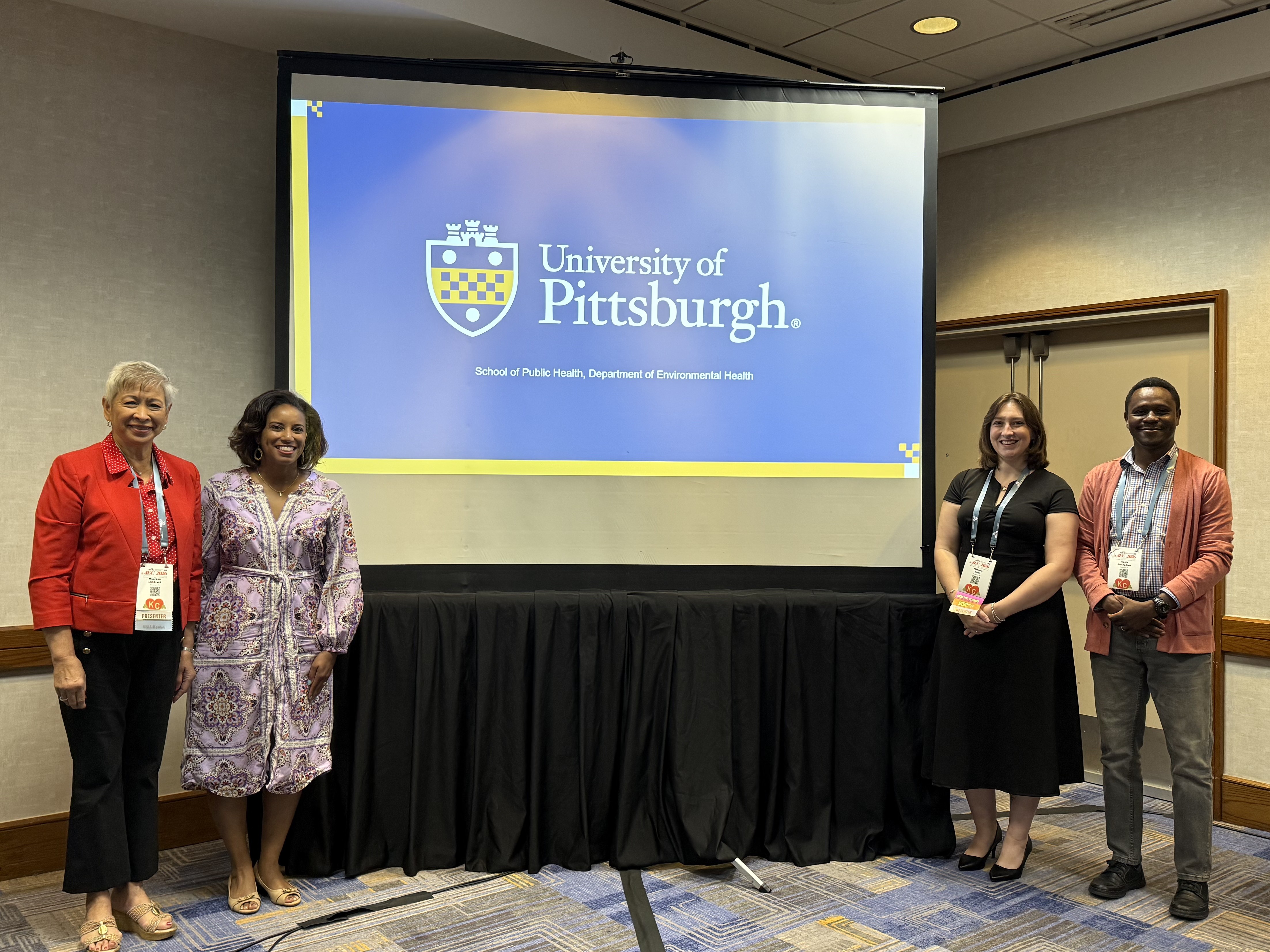 Maureen Lichtveld, MD, MPH; Tina Ndoh, PhD; Miranda Aman, MHA; and Nesta Bortey-Sam, PhD, Pitt Public Health, stand to the left and right of a slide that reads, "University of Pittsburgh."