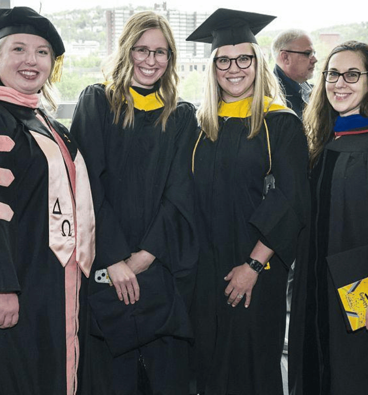 four Human Genetics faculty members in caps and gowns at 2022 graduation