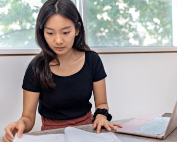 Student sitting at desk with laptop and notebook