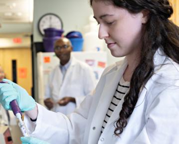 Female student weating white coat in lab