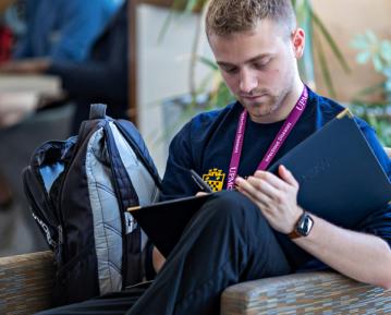 Student sitting with backpack looking at notebook