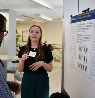 student presenting poster to another student
