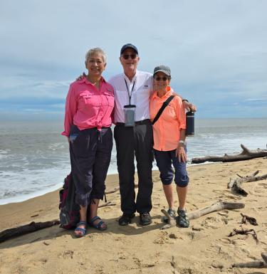 Pitt Public Health Dean Maureen Lichtveld and donors Lee and Isabel Foster standing on a beach.