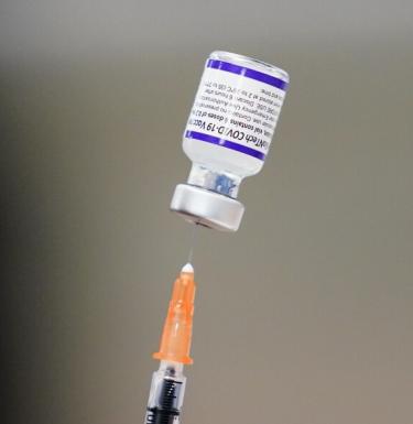A syringe is prepared with the Pfizer COVID-19 vaccine at a vaccination clinic.