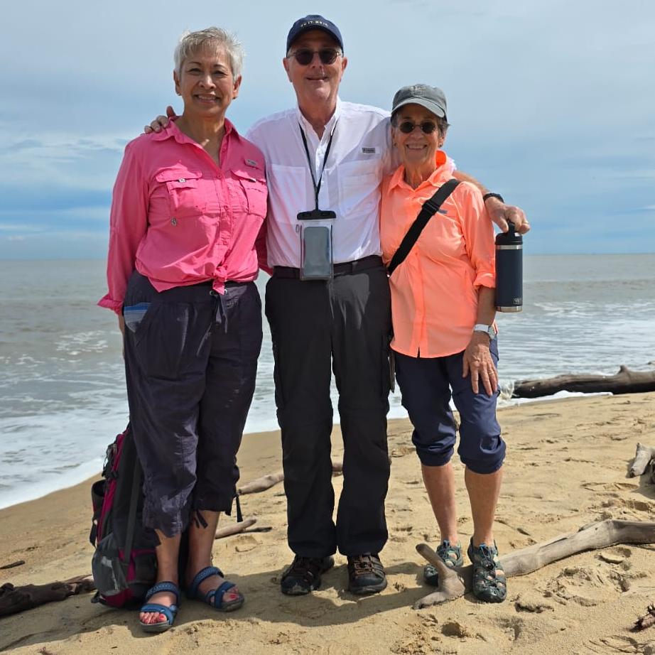 Pitt Public Health Dean Maureen Lichtveld and donors Lee and Isabel Foster standing on a beach.